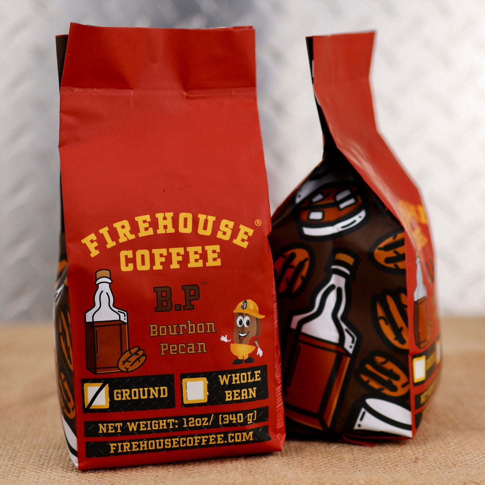 Firehouse Coffee Bourbon Pecan Flavored Coffee in a 12 oz red coffee bag featuring bourbon bottle and pecan graphics, bold Firehouse Coffee branding, and options for ground or whole bean coffee. The bag is displayed on a burlap surface with a soft industrial metal background, highlighting the rich, nutty bourbon pecan flavor profile.