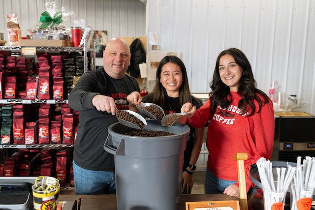 Firehouse Coffee team holding scoops of roasted coffee beans at the roastery in Maxatawny, Pennsylvania.