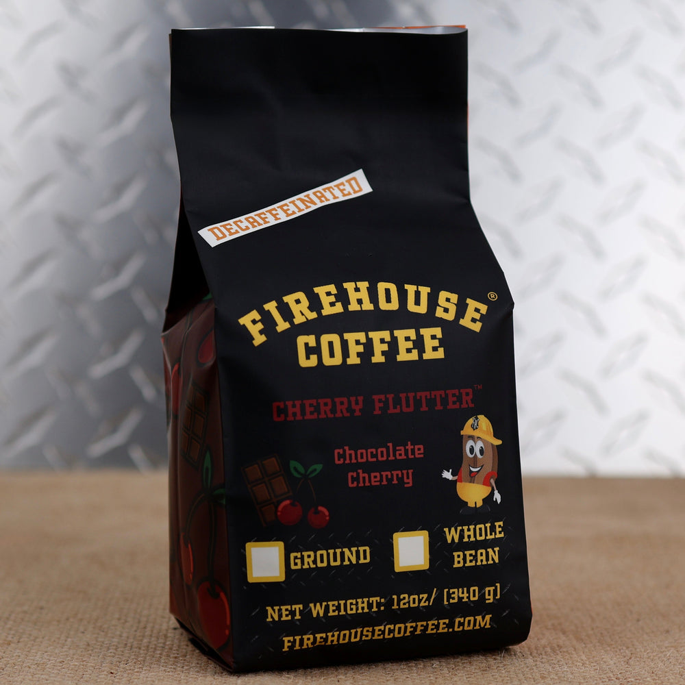 Firehouse Coffee Decaffeinated Cherry Flutter Chocolate Cherry flavored coffee in a 12 oz bag featuring rich chocolate and ripe cherry flavor notes. Swiss Water Process decaf coffee available in ground or whole bean, packaged in Firehouse Coffee's signature black bag with chocolate and cherry artwork and firefighter bean mascot.