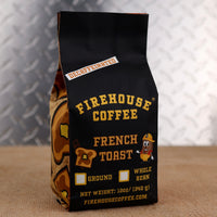 Firehouse Coffee French Toast Decaffeinated flavored coffee in a 12 oz bag, featuring the warm taste of buttery French toast, cinnamon, maple syrup, and vanilla. Swiss Water Process decaf coffee available in ground or whole bean with firefighter-themed packaging.