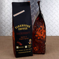 A decaffeinated bag of Firehouse Coffee Backdraft flavor next to a bag displaying its fire and bacon side pattern.