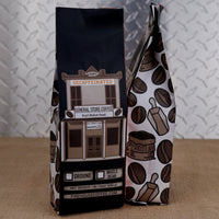 Firehouse Coffee General Store Coffee decaf Brazil medium roast in a 1 lb bag with a vintage storefront and coffee bean illustrations.