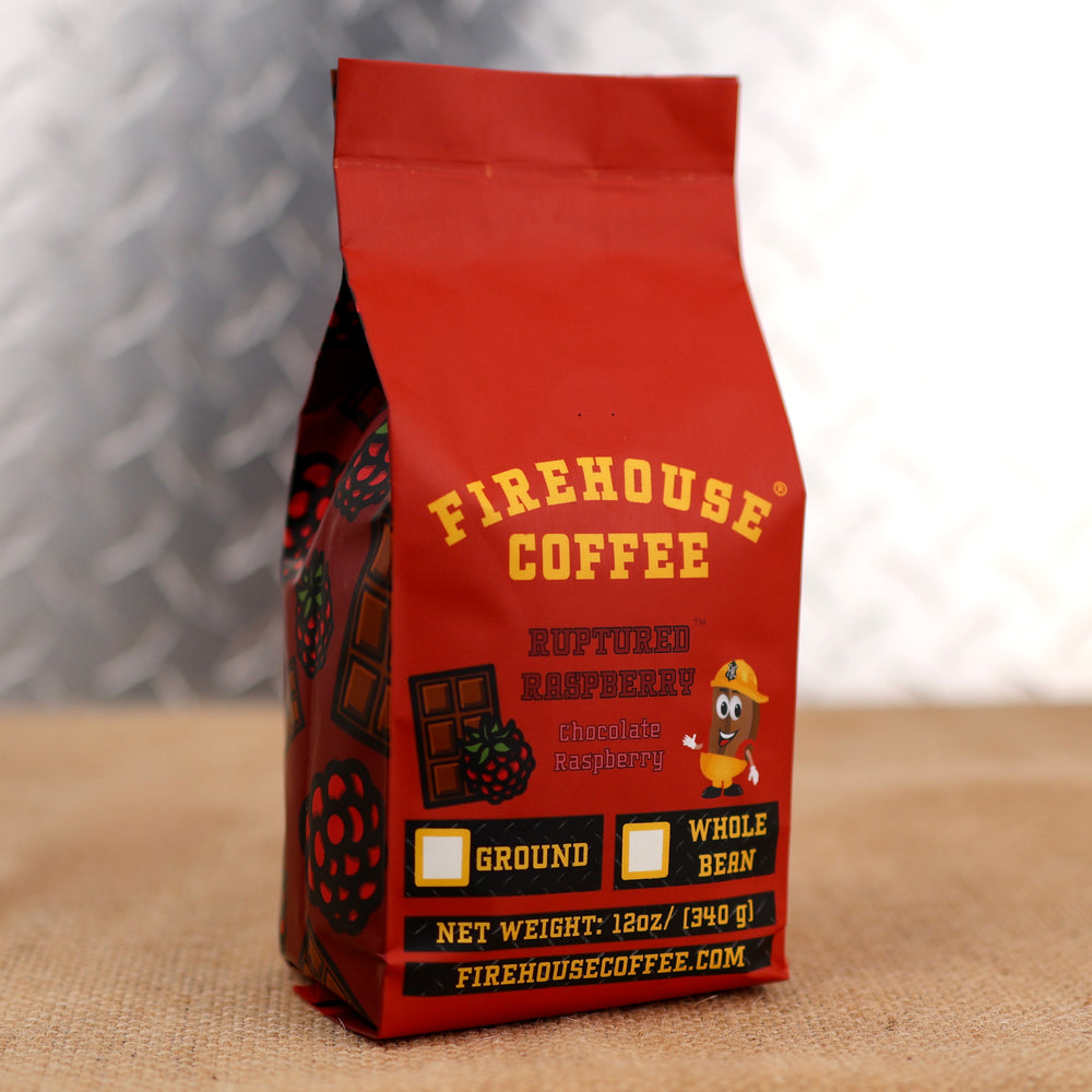 Red Firehouse Coffee bag with yellow text on a textured surface with raspberries and chocolate bars on the side.  