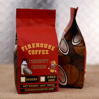 Firehouse Coffee Coconut Cream coffee bags shown from front and side angles, featuring red branded packaging with coconut imagery, hazard-style design accents, and 12oz ground and whole bean options.