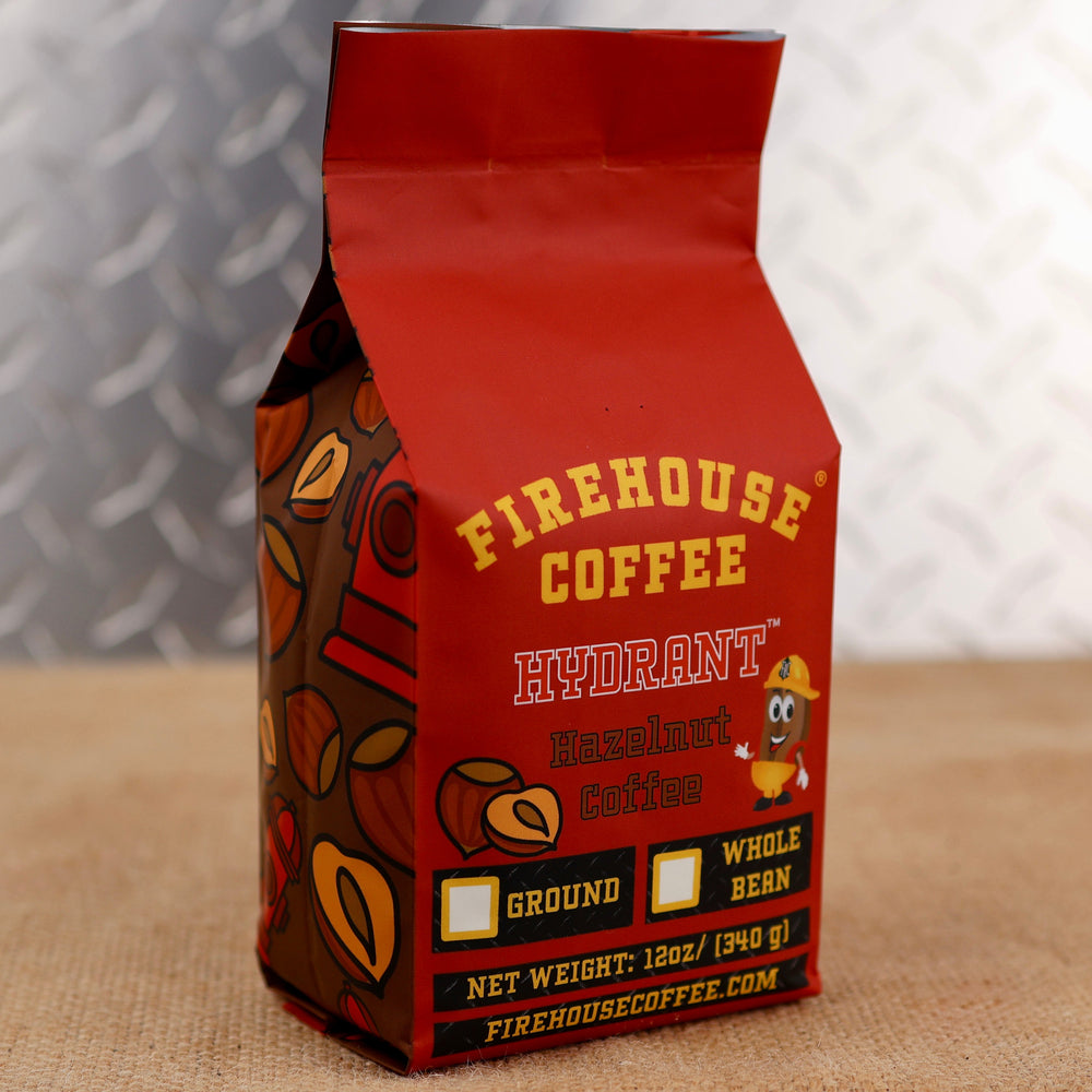 Firehouse Coffee Hydrant Hazelnut Coffee in a 12 oz red coffee bag featuring roasted hazelnut flavor, Firehouse Coffee branding, hazelnut graphics, and options for ground or whole bean coffee.