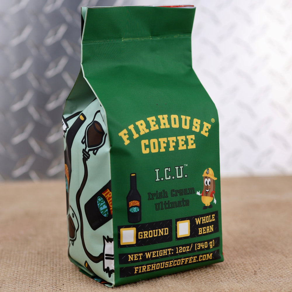 A green 12-ounce bag of Firehouse Coffee Irish Cream Coffee is displayed on a burlap-covered surface with a soft gray patterned background. The front label features the Firehouse Coffee logo, the product name I.C.U. Irish Cream Ultimate, an Irish cream bottle graphic, and the Firehouse coffee bean mascot wearing a firefighter helmet. The package includes checkboxes for ground or whole bean coffee, displays the net weight of 12 ounces (340 grams), and lists FirehouseCoffee.com at the bottom of the label.
